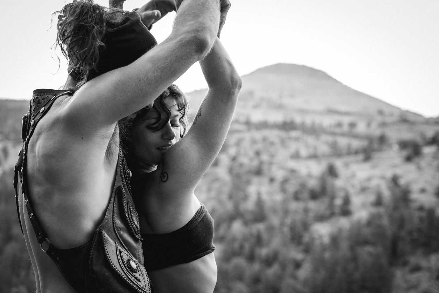Black and white athletic pose against mountain landscape backdrop.