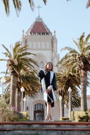 Graduate poses in front of Lone Mountain at the University of San Francisco. By Bay Area Graduation Photographer for her grad photos.
