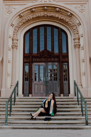 Graduate poses in front of steps of Lone Mountain building at the University of San Francisco. By Bay Area Graduation Photographer.