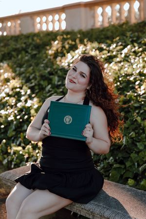 Graduate holds up her diploma during her grad photoshoot at the University of San Francisco. By Bay Area Graduation Photographer.