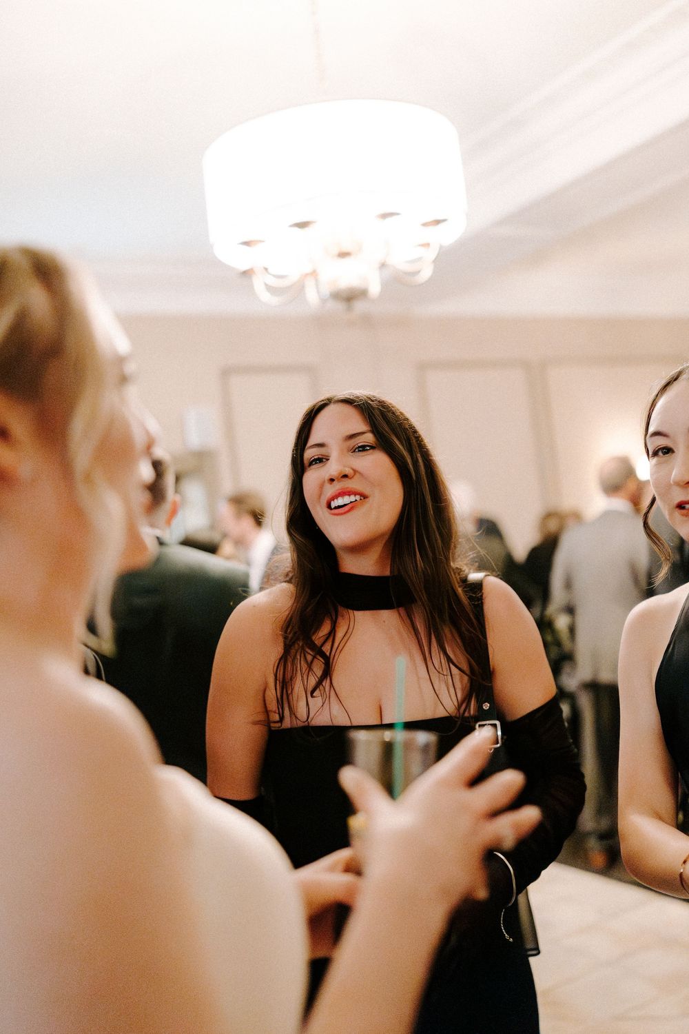 People dancing and celebrating at an elegant indoor party with white ceiling lights.