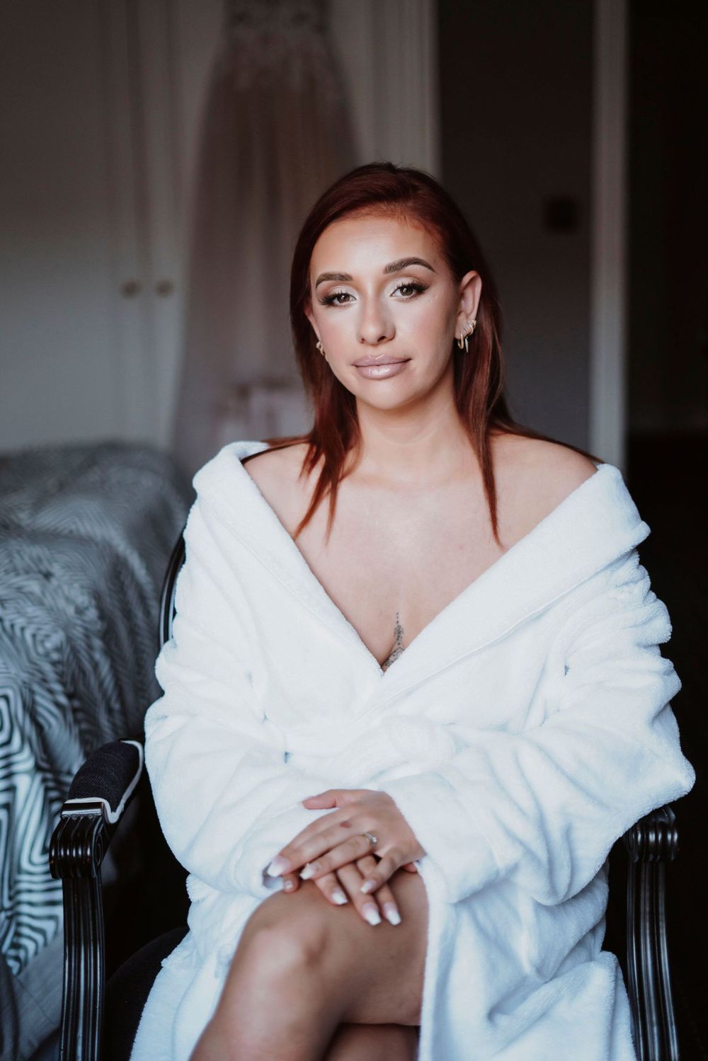 Portrait de la mariée pendant les préparatifs, peignoir blanc, maquillage naturel, ambiance intime et douce.