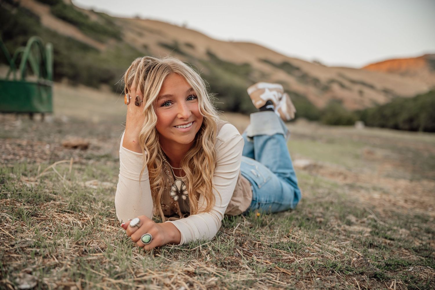 A casual portrait in a grassy field with mountains in the background.