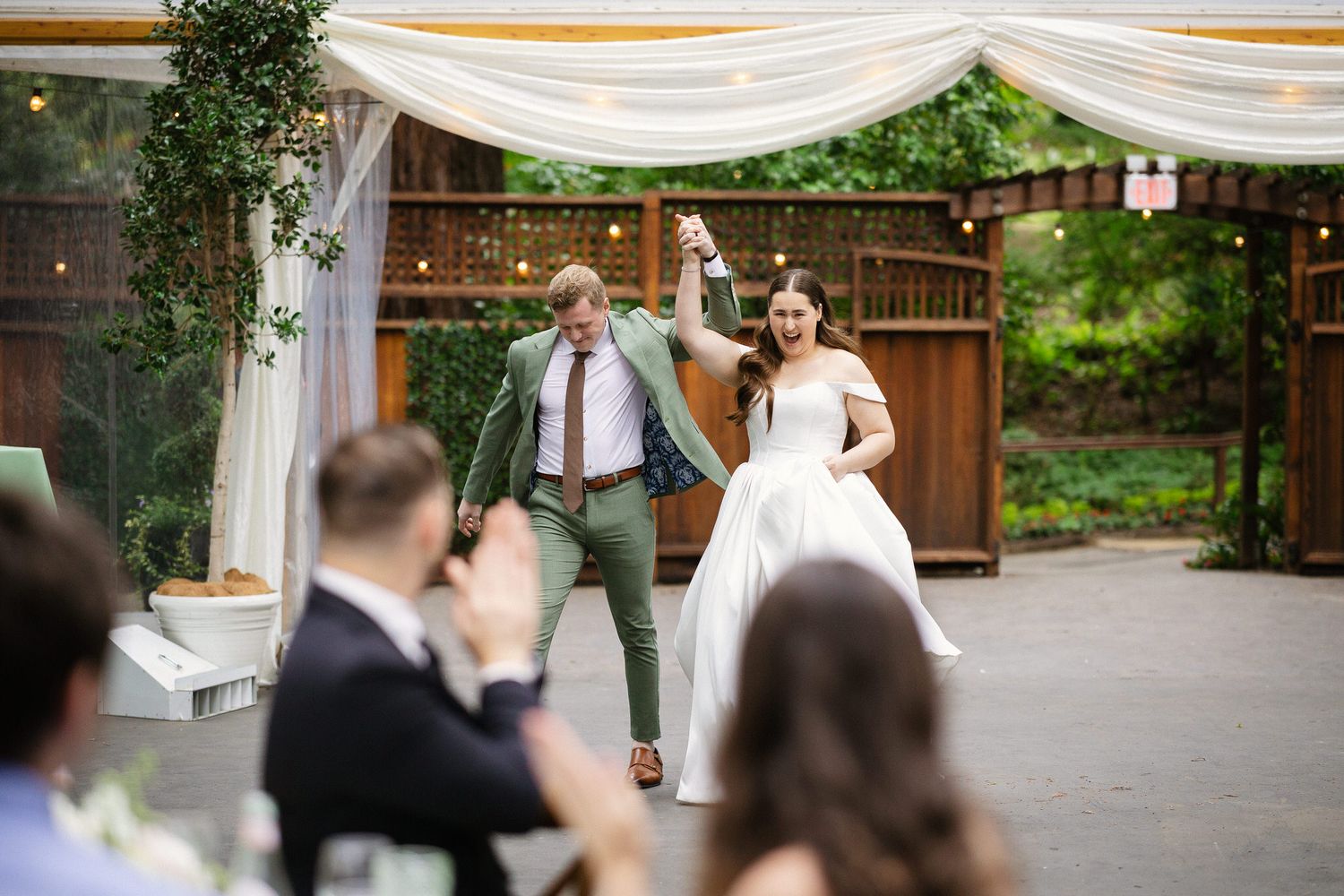 A newlywed couple stands at the bottom of a staircase at Nestldown surrounded by towering trees and greenery.