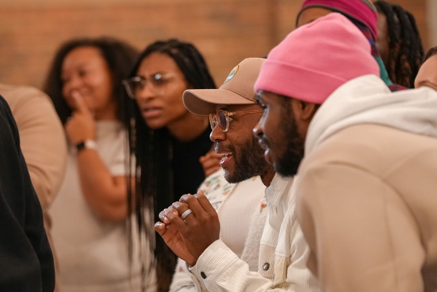 Group of people engaged in lively conversation at an indoor gathering, smiling and listening attentively.