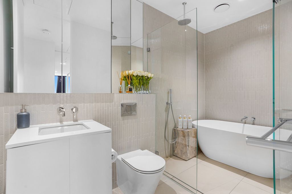 Luxurious bathroom featuring freestanding tub, glass shower enclosure and white vanity.