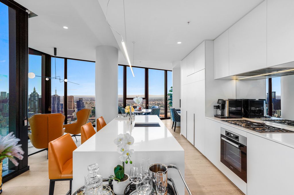 Modern open concept kitchen and dining area with floor-to-ceiling windows and orange chairs.