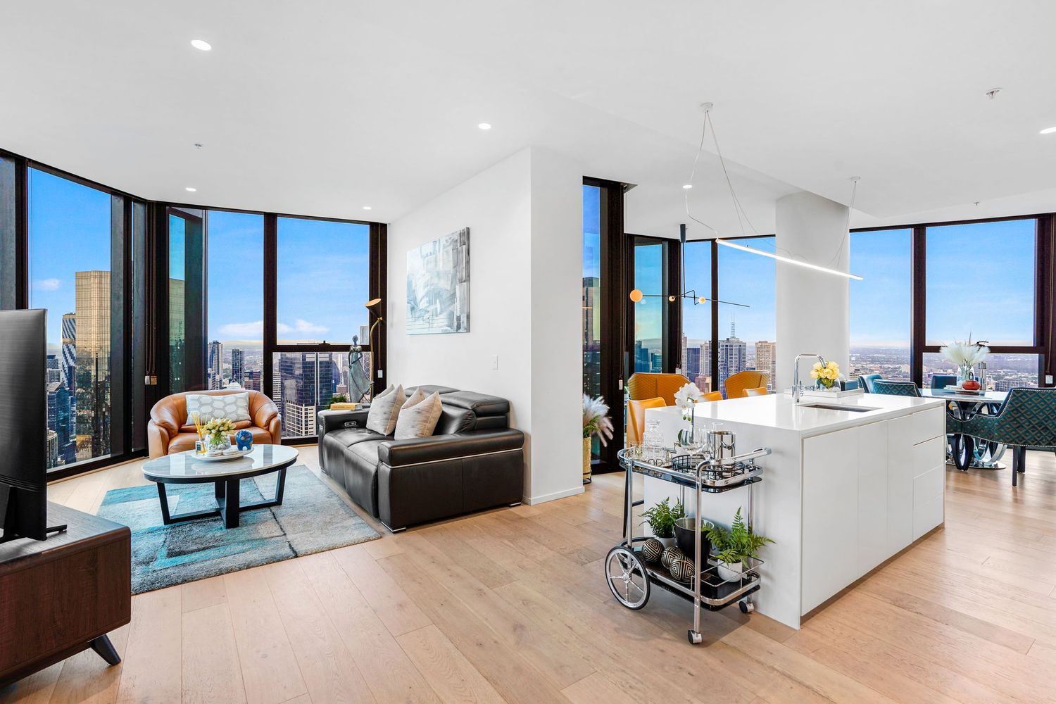 Modern open-concept living room and kitchen with stunning city views through large windows.