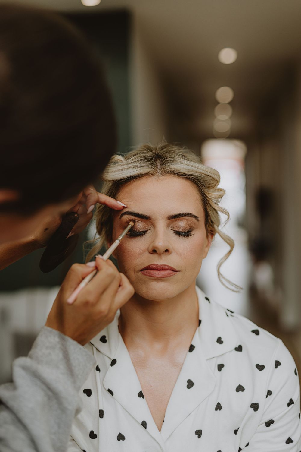 Wedding day makeup application on someone wearing a heart-patterned robe.