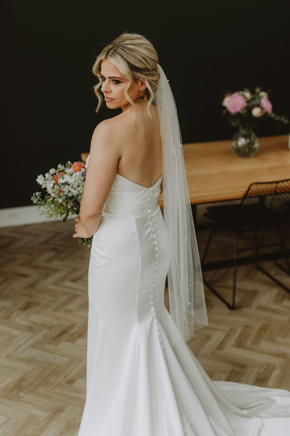 Classic white wedding dress with buttons and veil photographed in natural light.