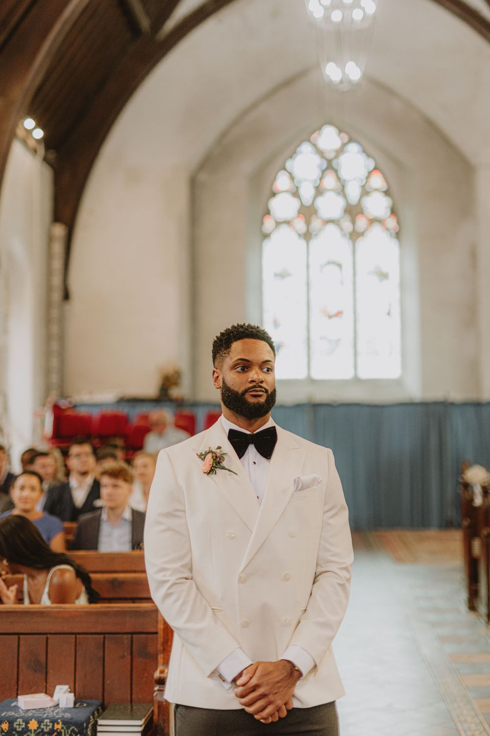 Traditional church interior with wooden pews and stained glass windows during wedding ceremony.