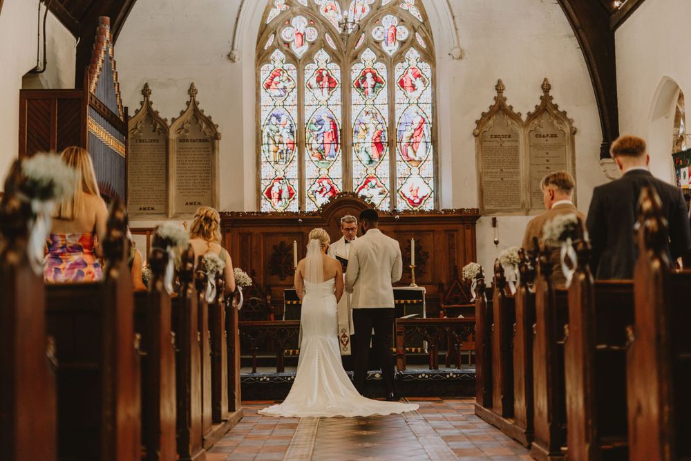 Church wedding ceremony with beautiful stained glass windows and wooden architecture.