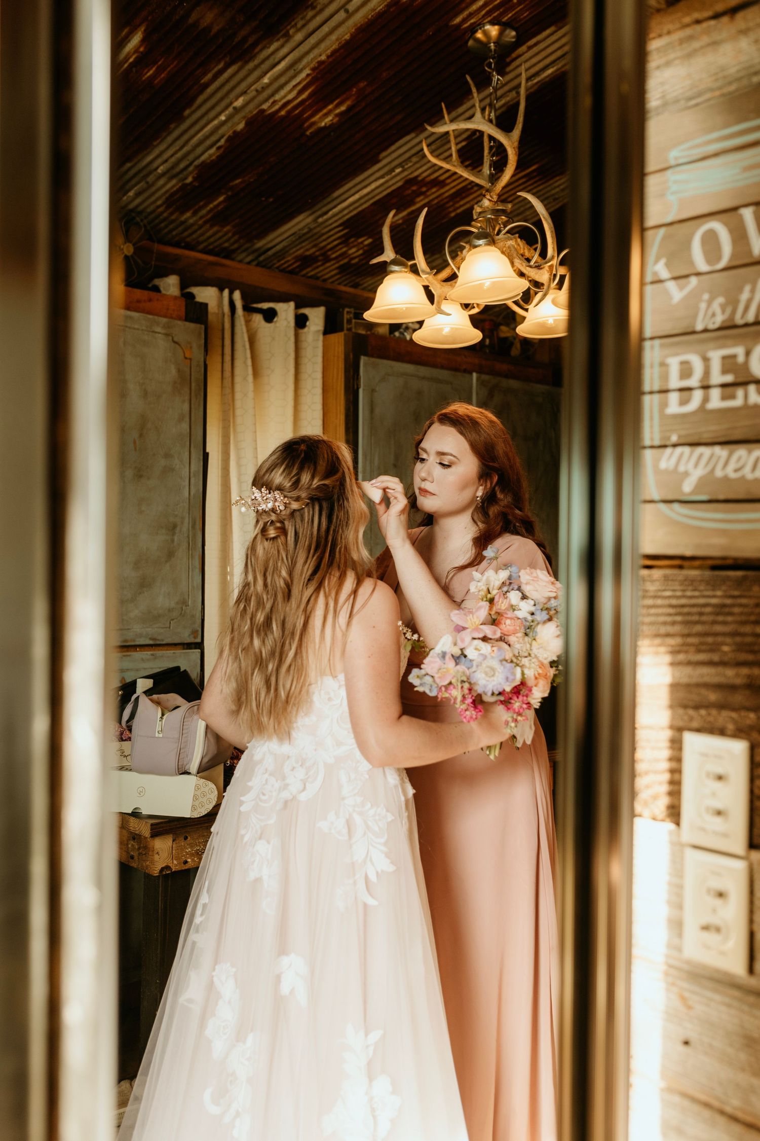 Photograph of bride and bridesmaid getting ready at the barn at big oak in franklin georgia