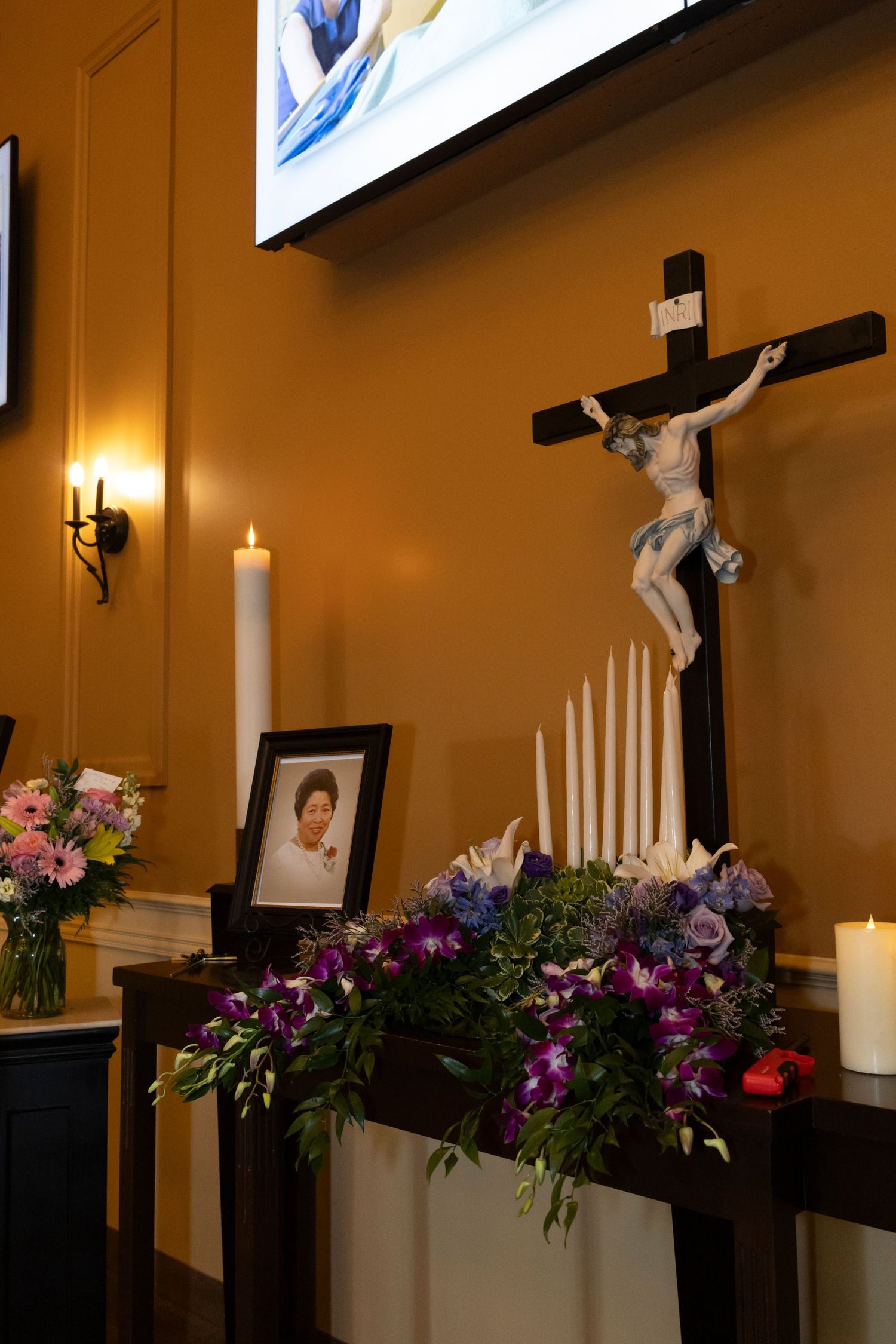 Photo of a woman next to purple flowers and candles