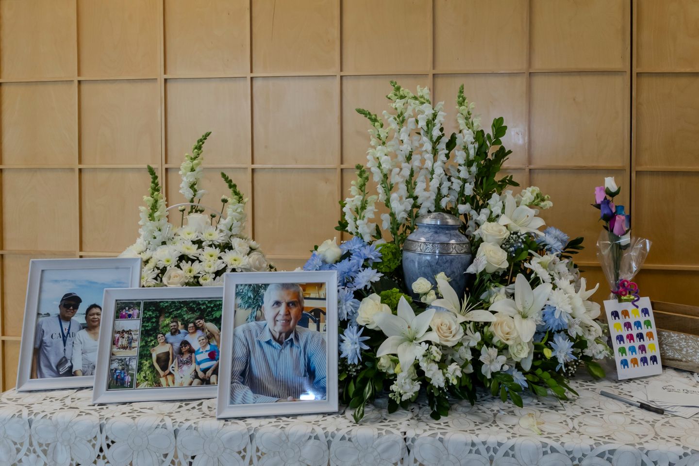 Table with blue urn surrounded by white flowers & other picture frames