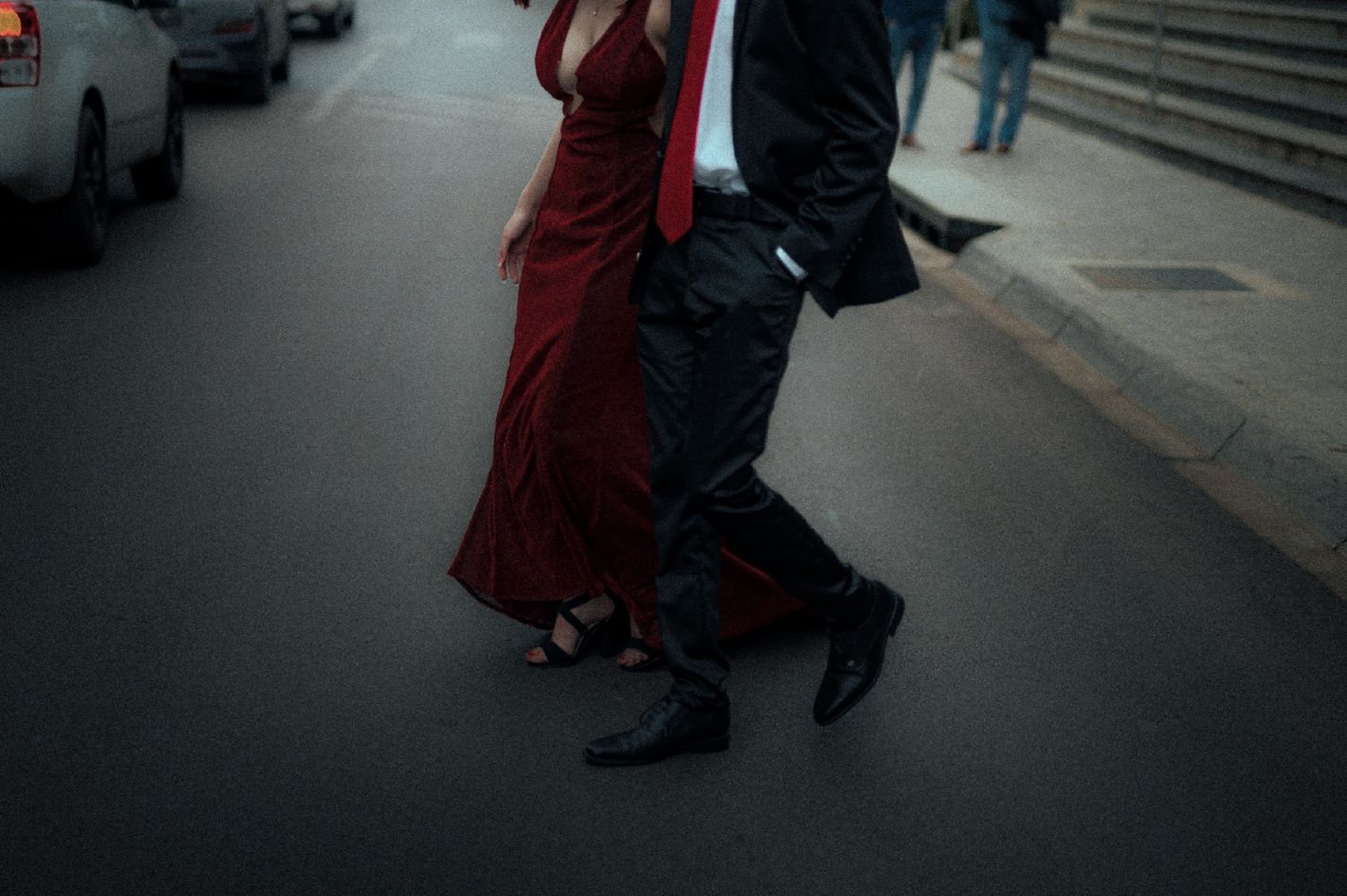 Two people walking together on a street, with a red dress billowing in motion.