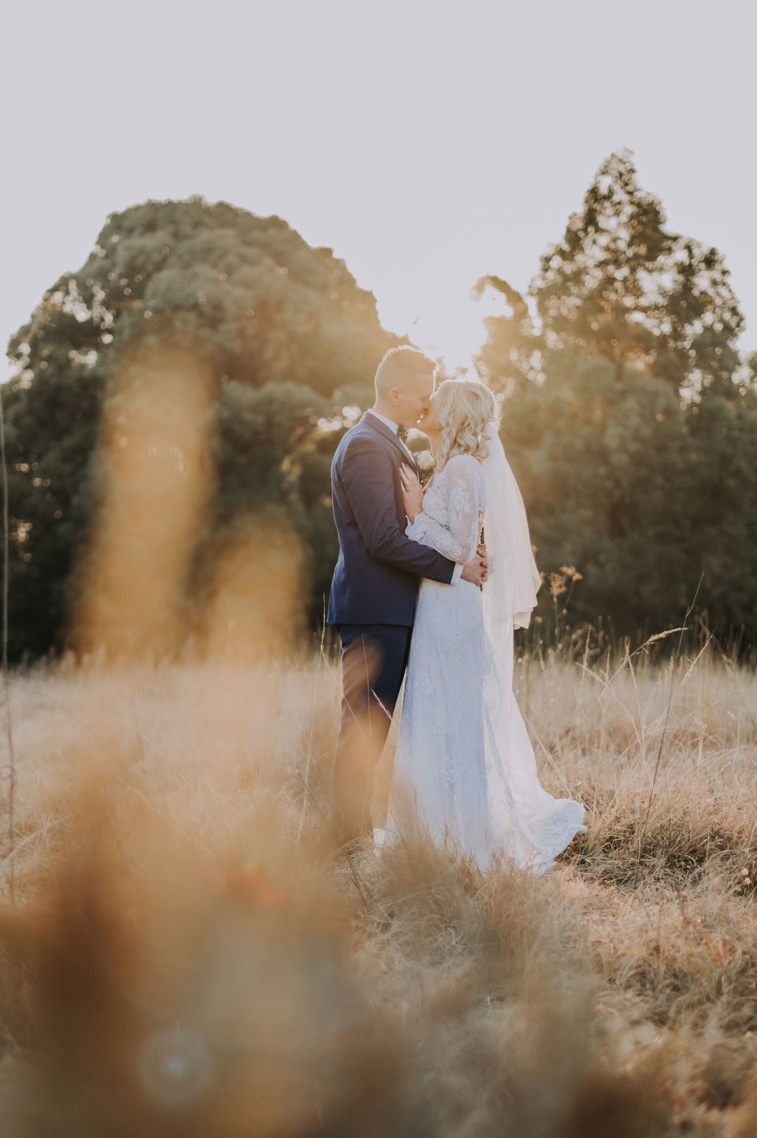 A romantic sunset portrait of a couple embracing in a golden field.