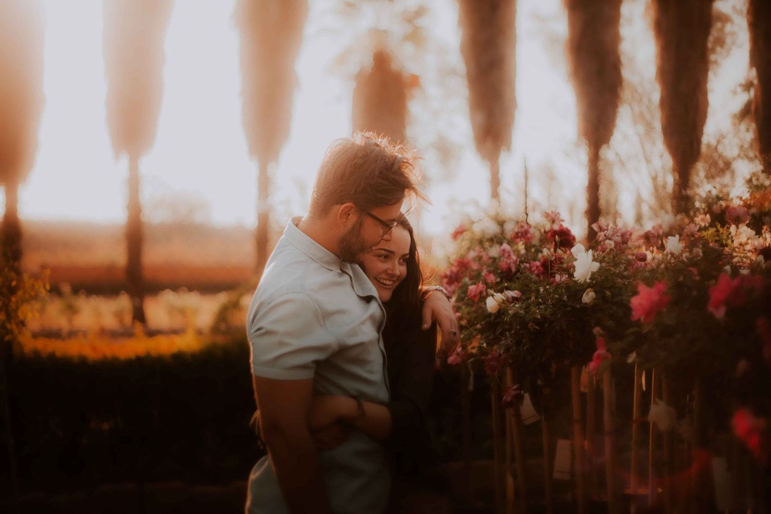 A couple sharing a tender moment among flowers during golden hour.