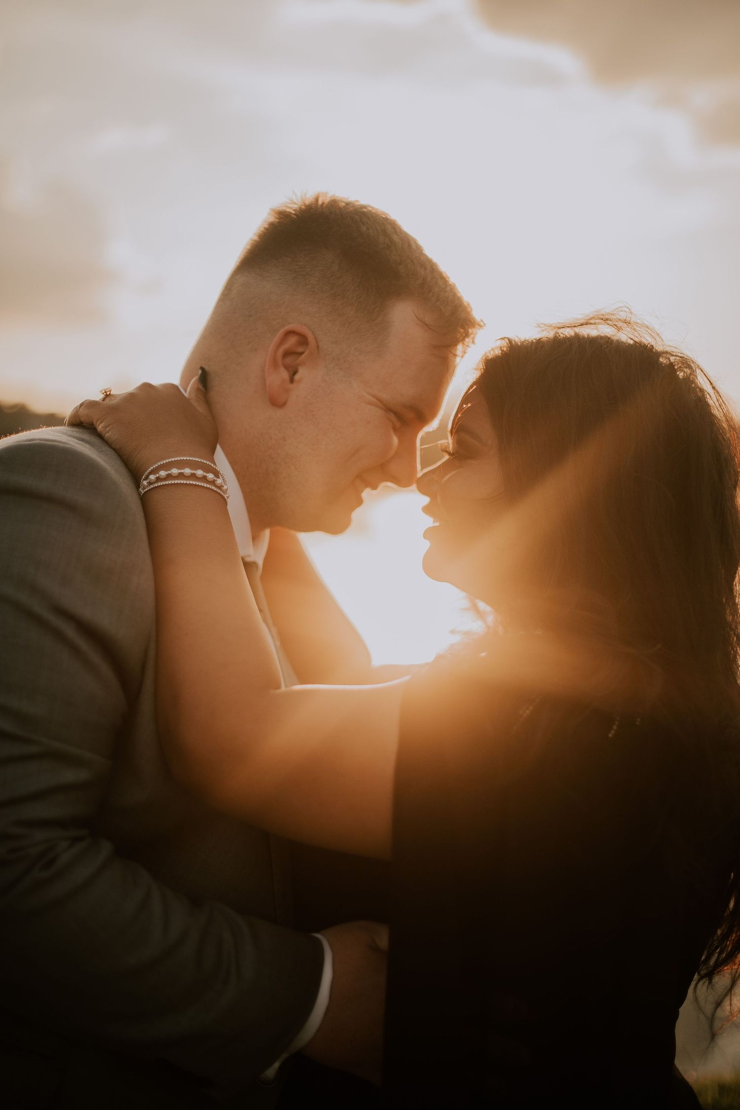 A tender romantic moment captured between a couple during golden hour with lens flare.