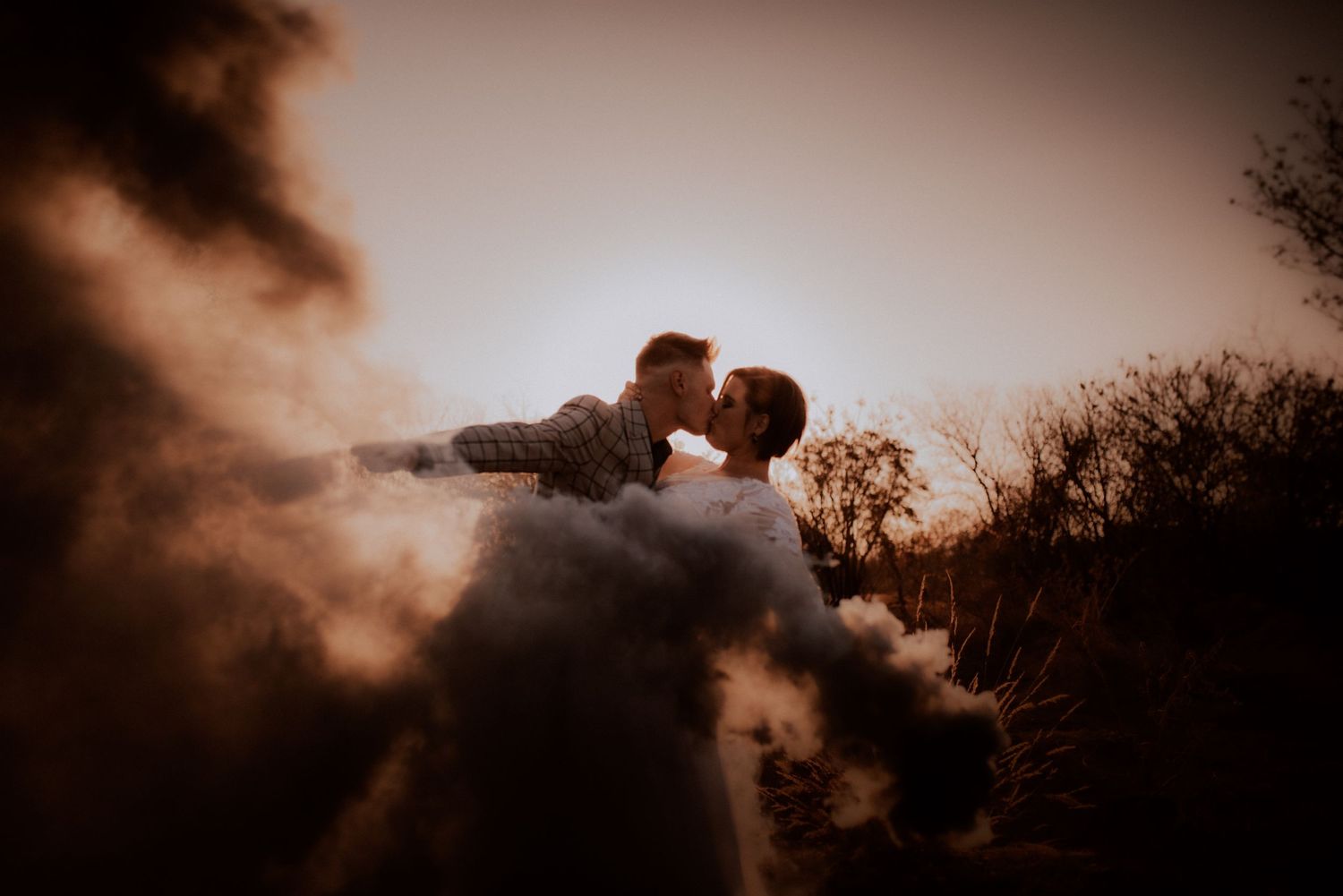 A romantic sunset silhouette of a couple in an intimate moment against a dramatic sky.