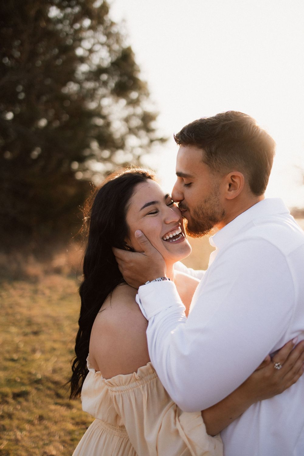Romantic couple sharing an intimate moment at sunset with joyful laughter and tender embrace.