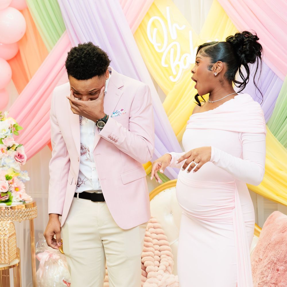 Emotional expecting couple reacting with surprise and joy at a colorful pastel-themed baby shower celebration.