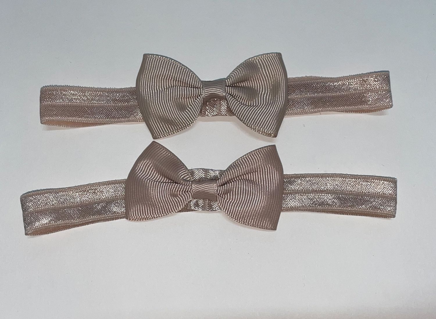 Series of taupe bow ties mounted on elastic bands.