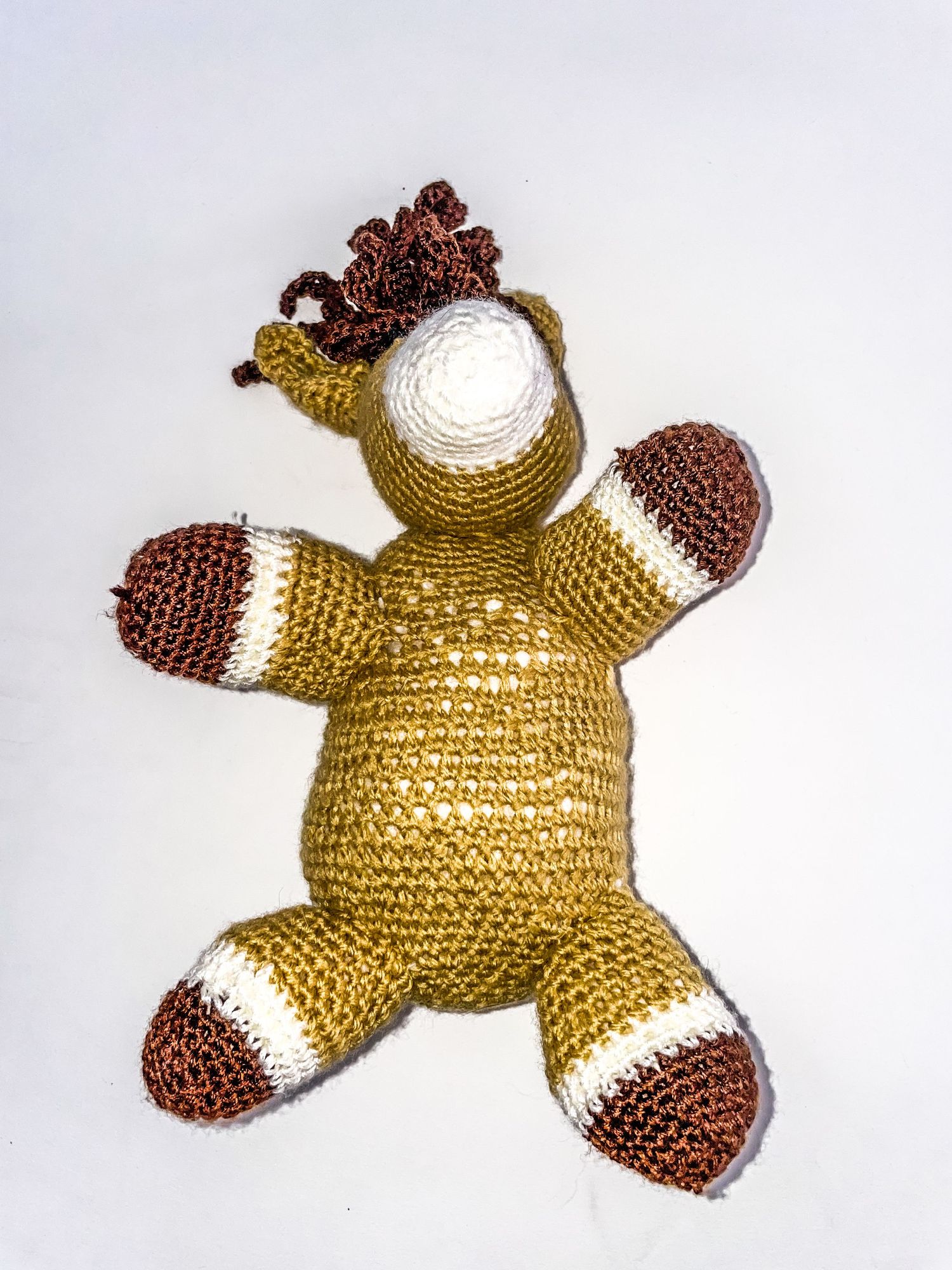 Hand-crocheted golden teddy bear plush toy with brown and white accents.
