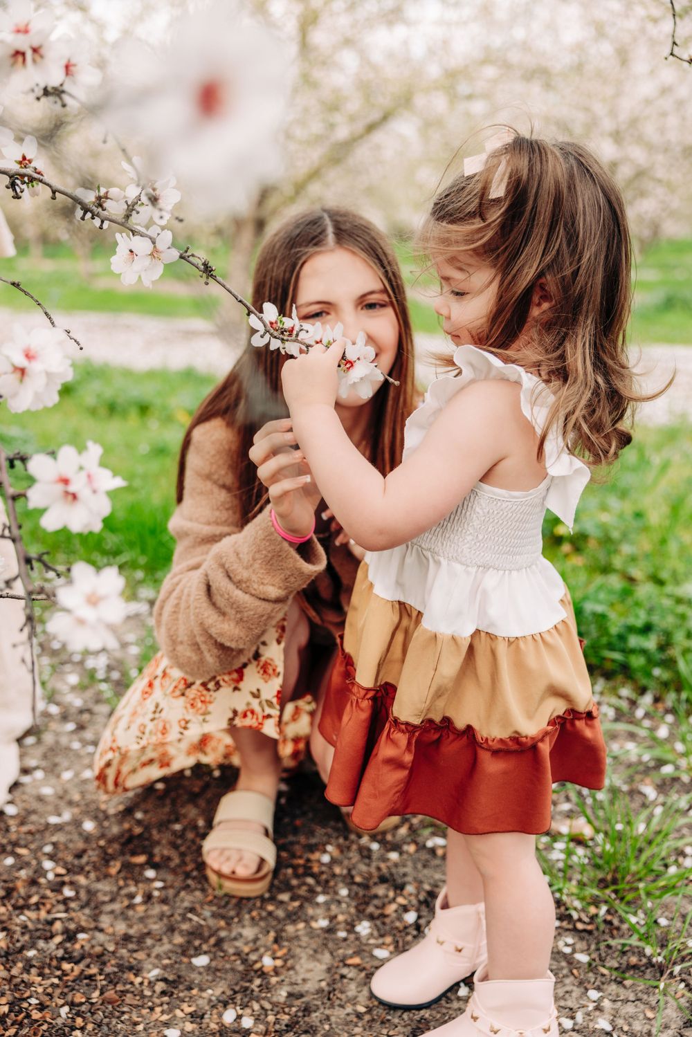A joyful springtime moment shared beneath blooming cherry blossoms in a garden setting.
