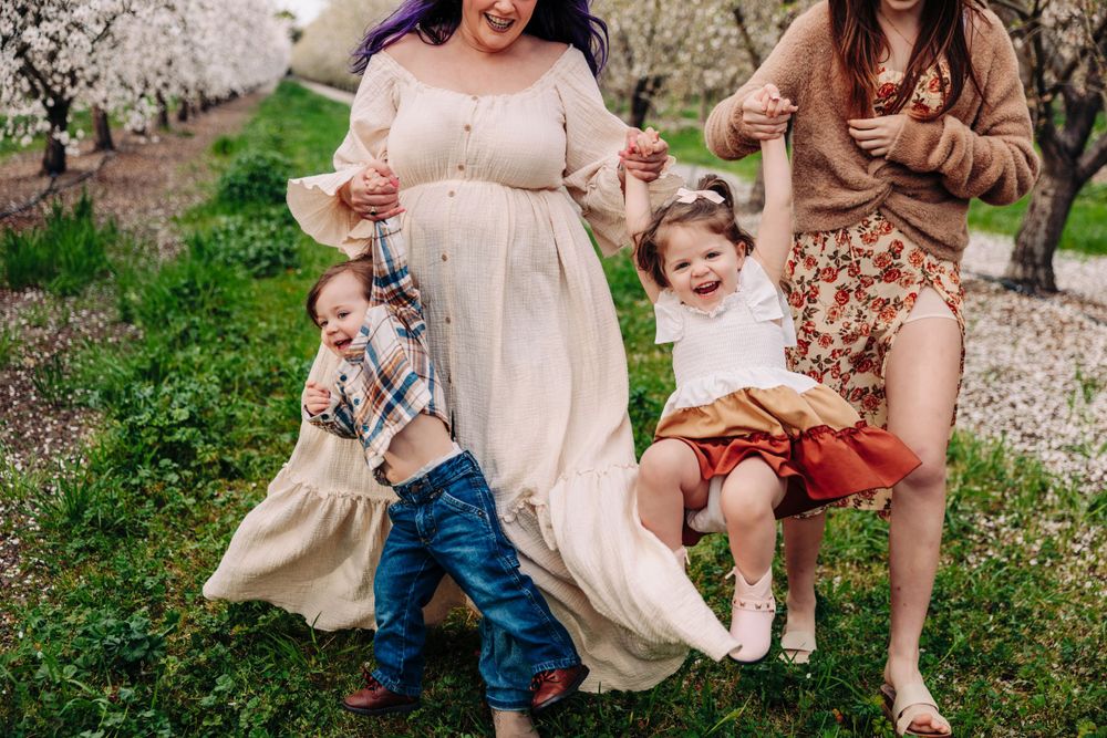Candid moment of laughter and play during a spring photo session amid flowering trees.