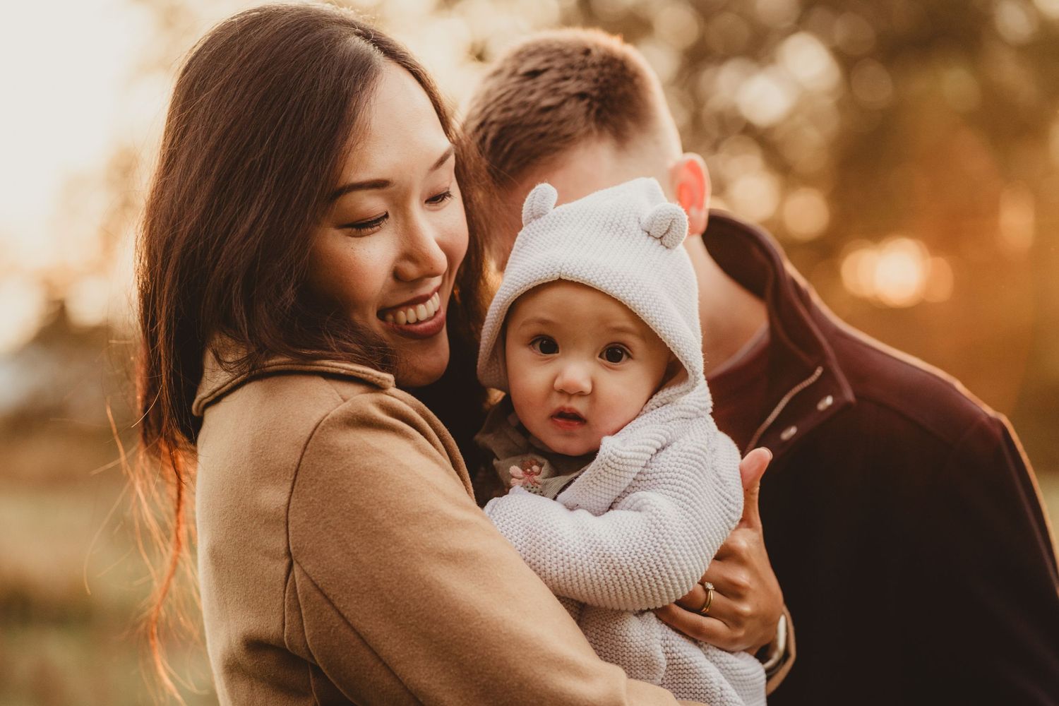 Mother cuddling her baby in the soft evening light during a relaxed family photoshoot in Bishops Stortford.