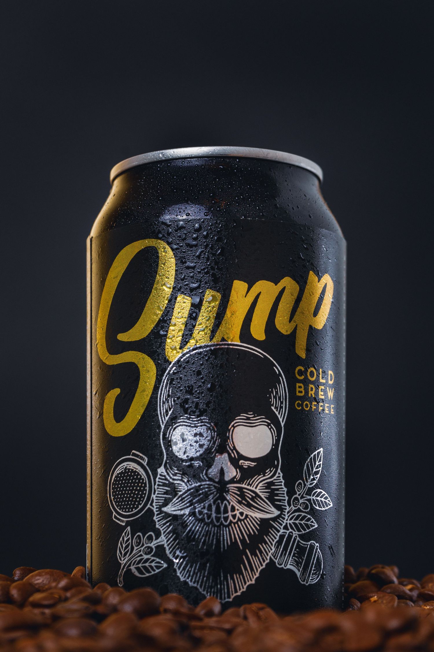 Black can of Sump cold brew coffee with yellow logo and skull design sits among scattered coffee beans on dark background.