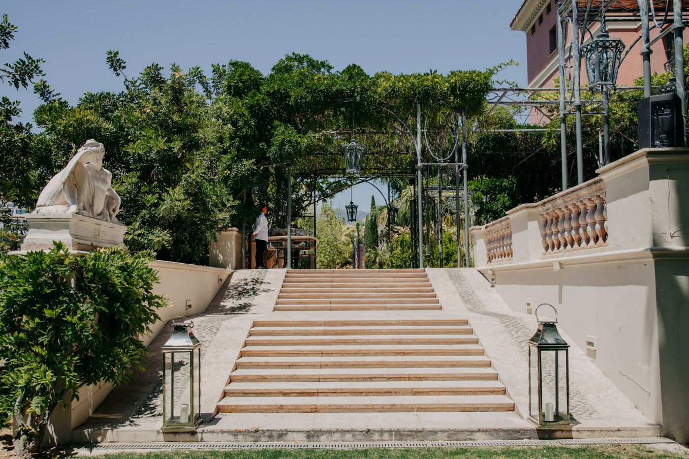 Elegant outdoor stone staircase with ornate lanterns and greenery at a luxury venue.