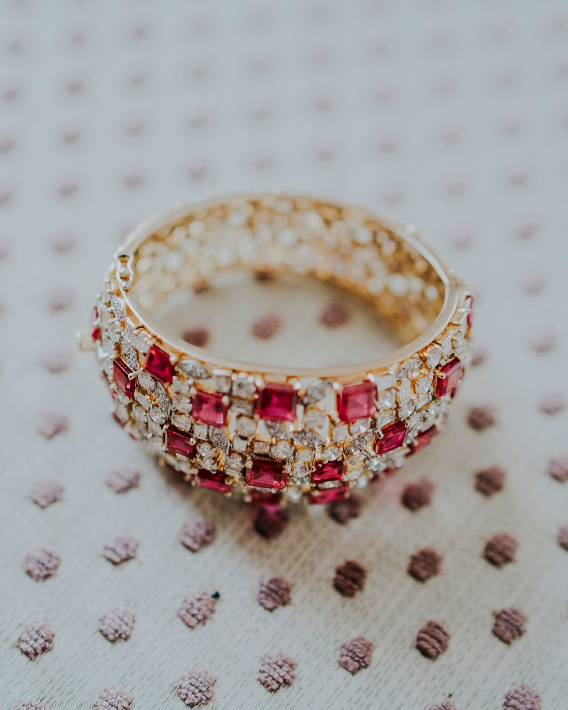 An elegant gold ring adorned with square-cut ruby gemstones and clear crystals in a delicate filigree pattern.