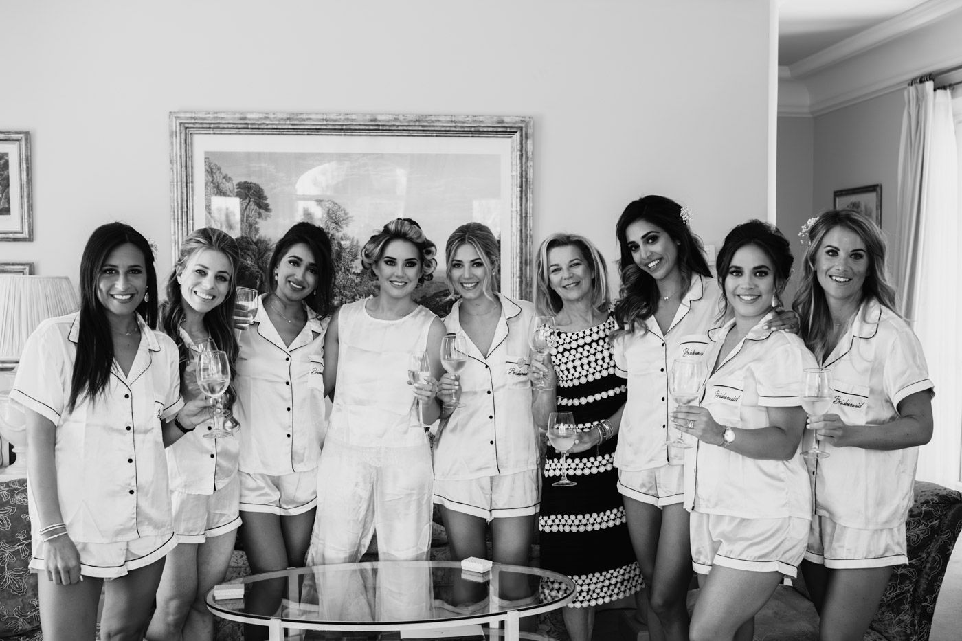 A group photos taken in black and white shows people in white outfits standing together in a room.