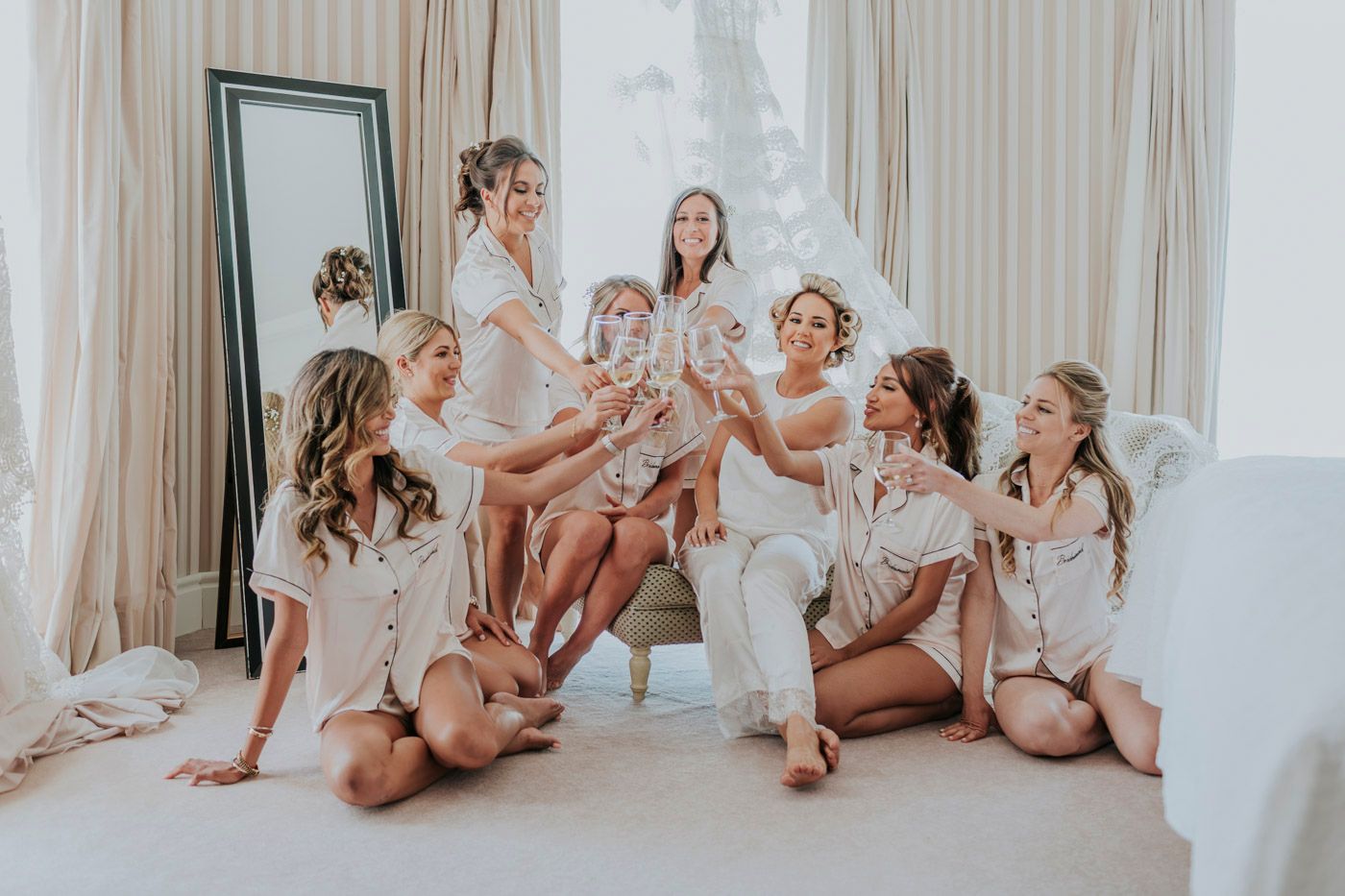 Candid moment of bridal party in matching robes lounging together.