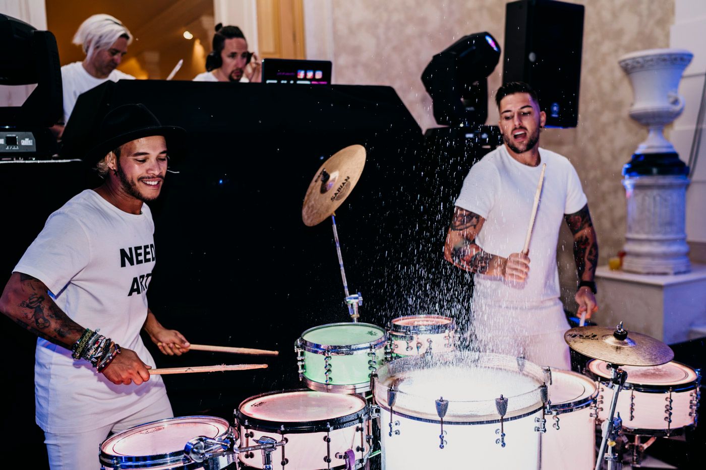 Two musicians play drums and percussion instruments during a lively performance.