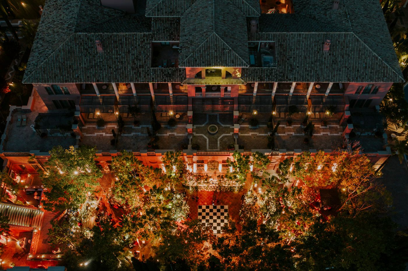 Aerial view of an illuminated urban terrace at night with colorful lights and trees creating a magical ambiance.