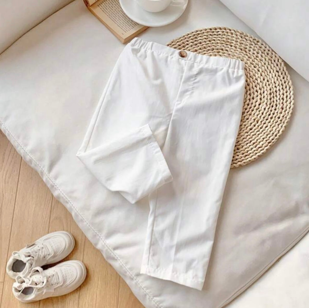 White baby clothing and shoes arranged neatly on wooden surface.