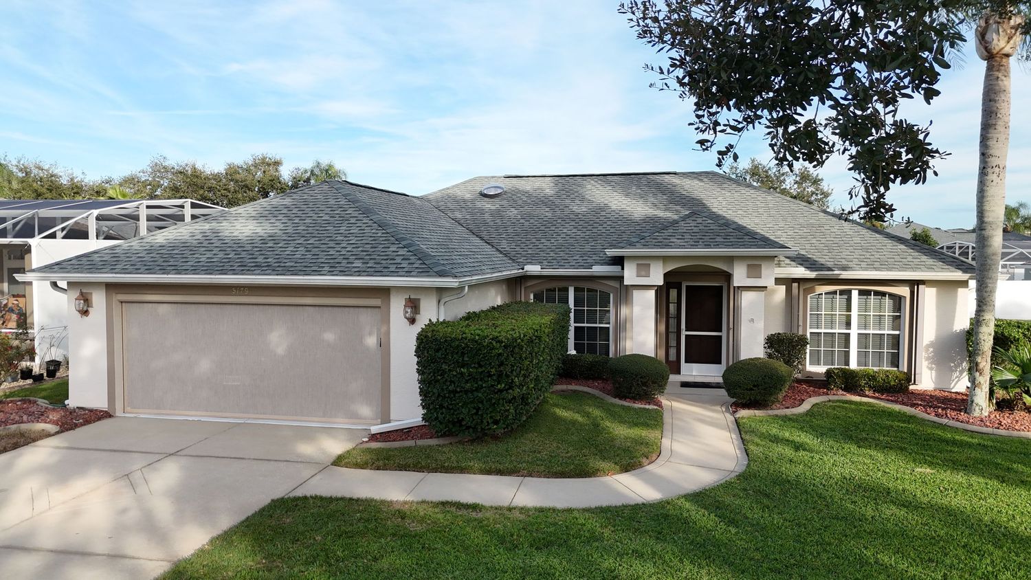 Modern ranch-style house with curved driveway and attached garage in Florida neighborhood.