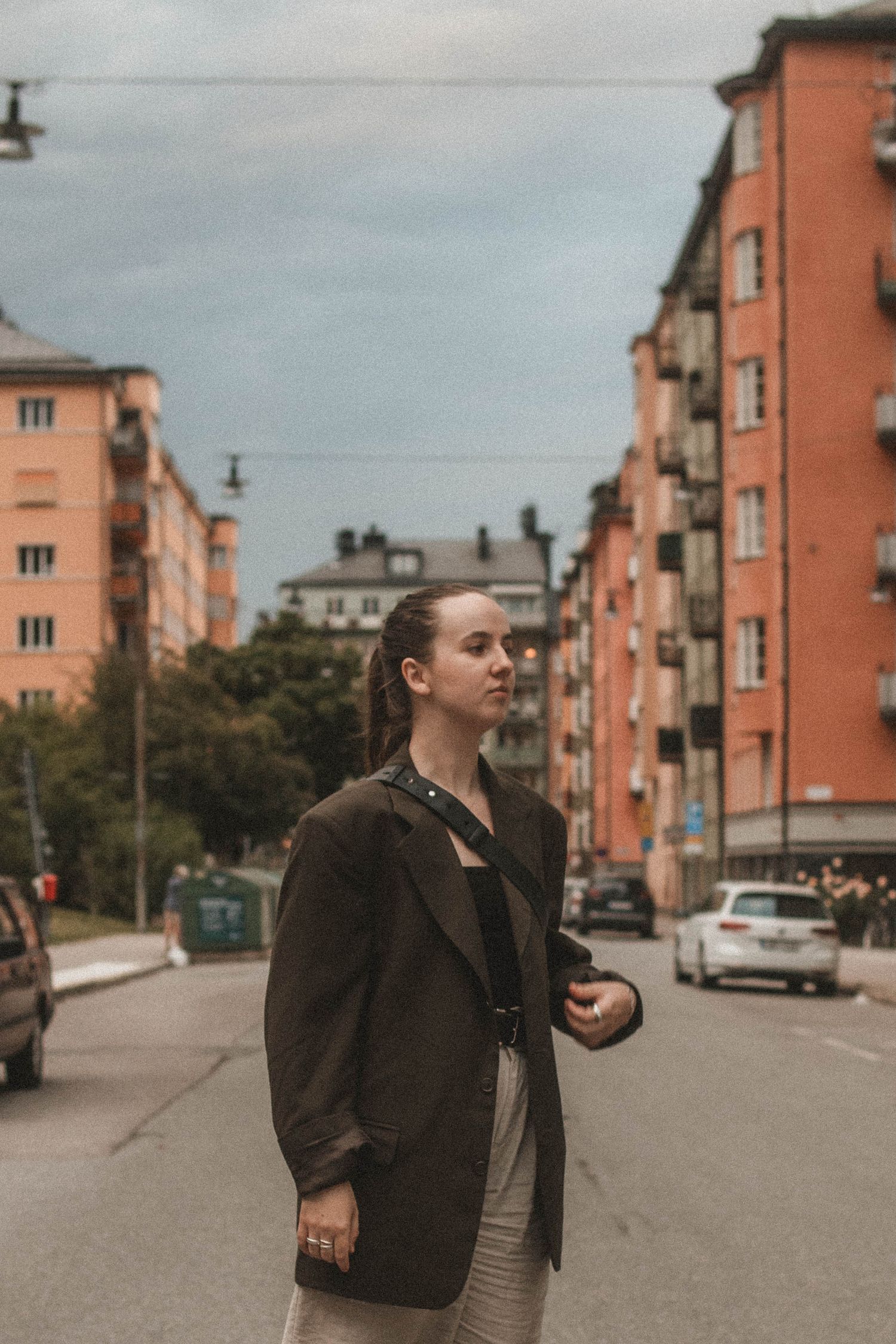 Urban street scene with peach-colored apartment buildings and a figure in a dark coat.