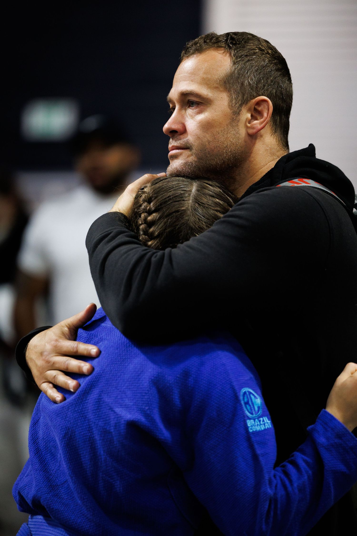 Competitors in blue gis embrace after a jiu-jitsu match showing great sportsmanship.