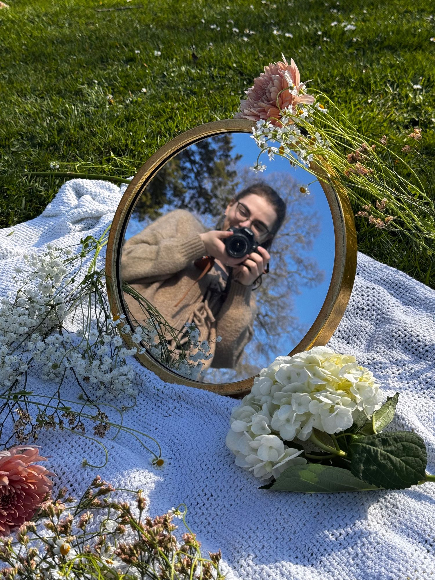 Photo of a photographer taking a photo of a mirror surrounded by flowers.