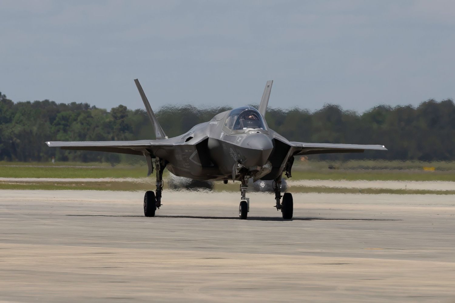 An F-35 Lightning II stealth fighter jet taxiing on runway with landing gear down.