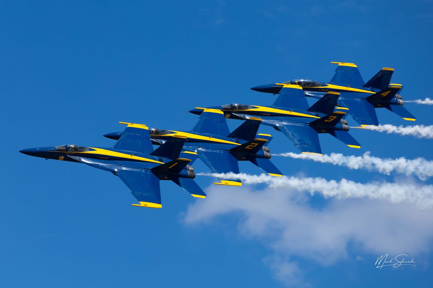 Blue Angels fighter jets flying in formation with trailing smoke during an aerial demonstration.