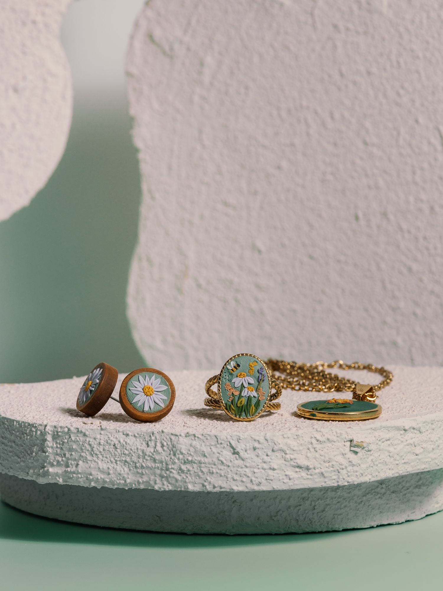 Collection of delicate gold rings arranged on textured white surface with soft shadows.