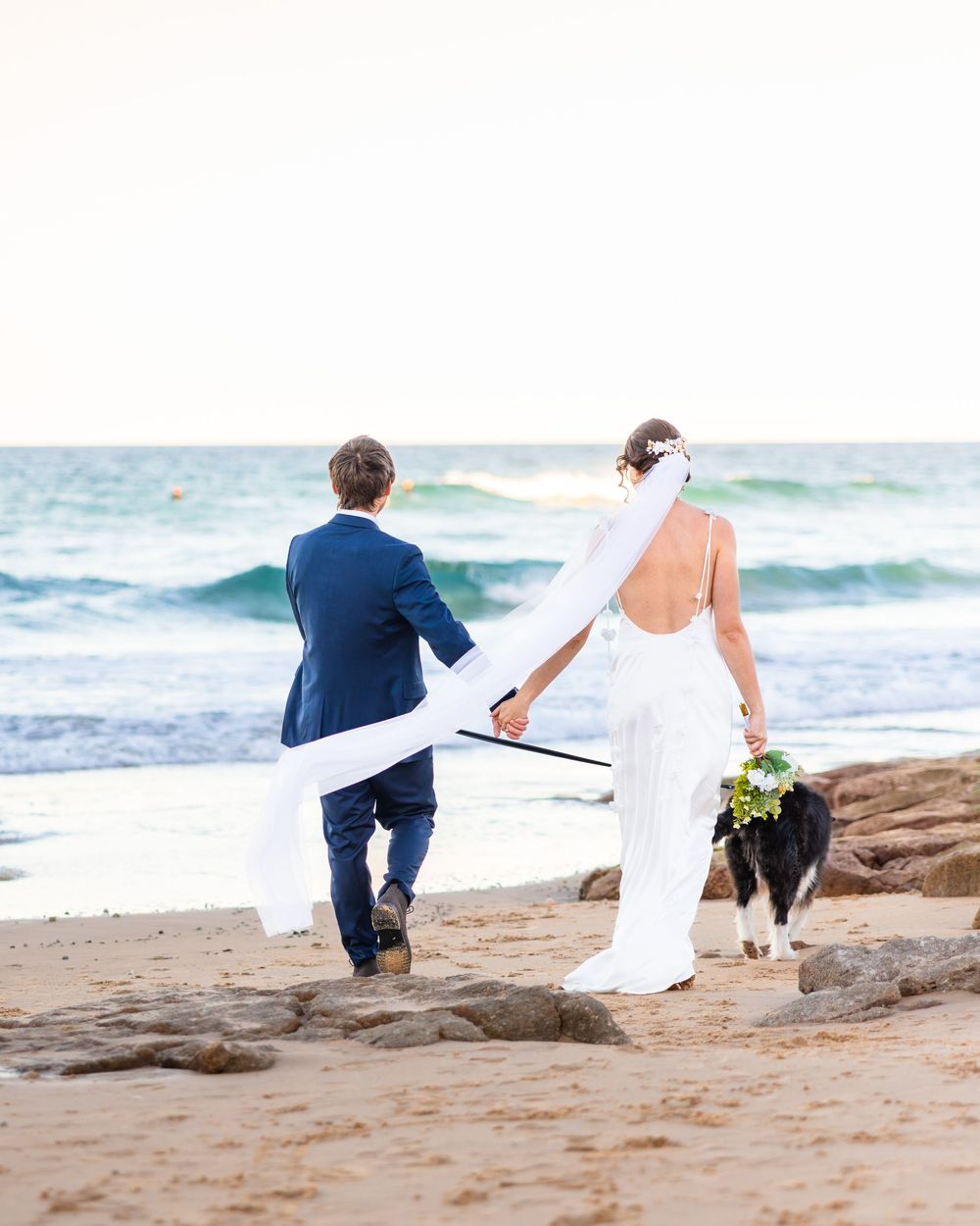 Married couple and their dog running away on a Sunshine Coast Beach.