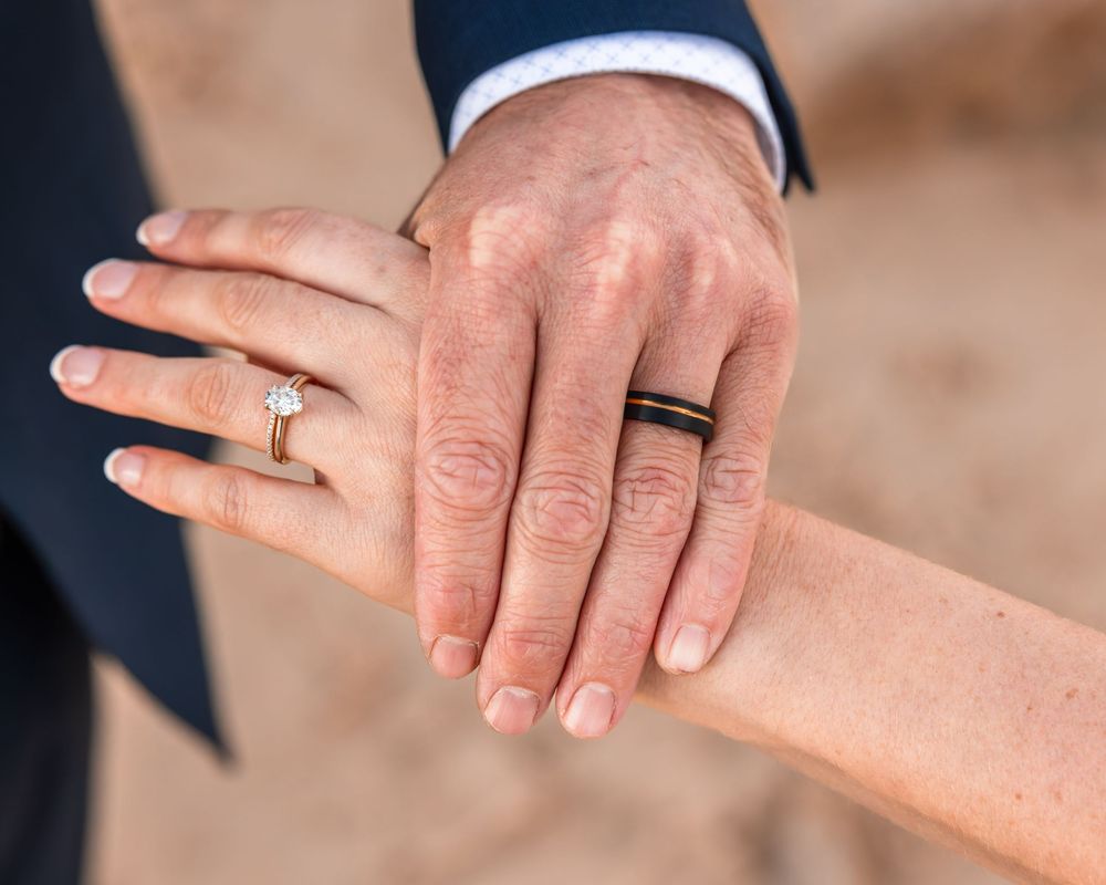 husbands handover his wife's hand showing both of their wedding rings