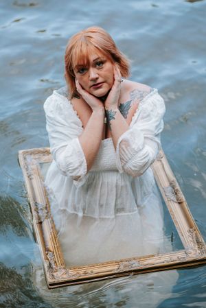 An artistic water portrait featuring a white dress and vintage picture frame.