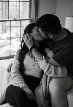 Black and white intimate portrait of couple sharing tender moment by window.